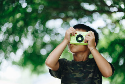 Boy playing with toy camera at park