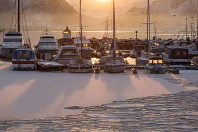 Boats moored in harbor at sunset