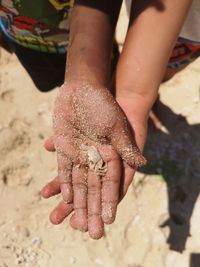 High angle view of hands on wet sand