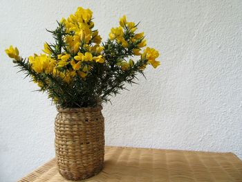 Yellow flowers in wicker vase on table