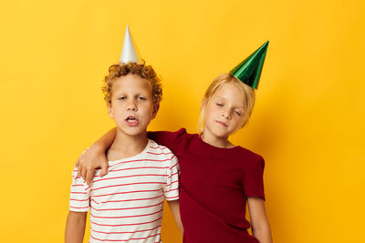 Sibling wearing party hat against colored background