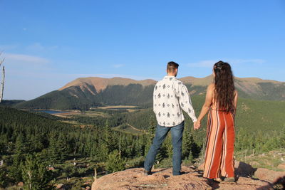 Rear view of friends standing on mountain against sky