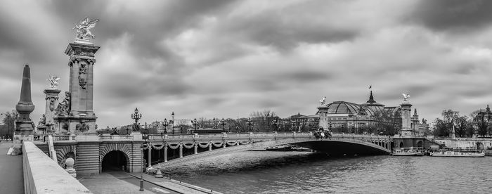 Bridge over river against cloudy sky