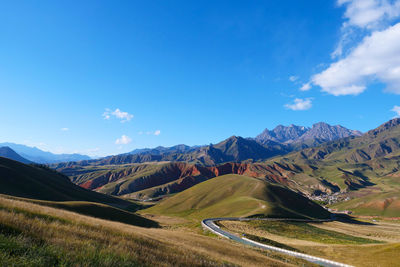 Scenic view of landscape and mountains against blue sky