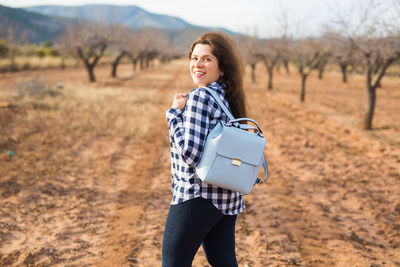 Portrait of smiling young woman standing on field