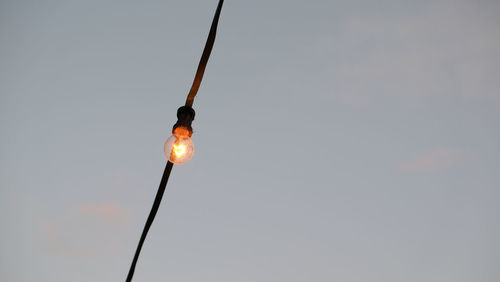 Low angle view of illuminated light bulb against sky