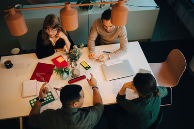 High angle view of multi-ethnic business team discussing while sitting at desk in creative office