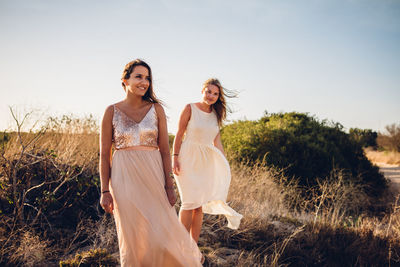 Full length of friends standing on field against sky