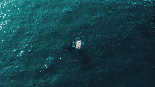 Aerial view of woman on inflatable raft in sea