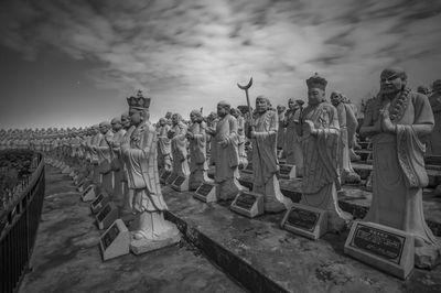 Various statues in row against sky