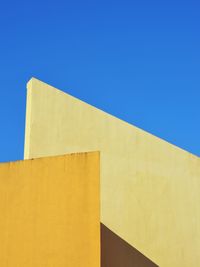 Low angle view of yellow building against blue sky