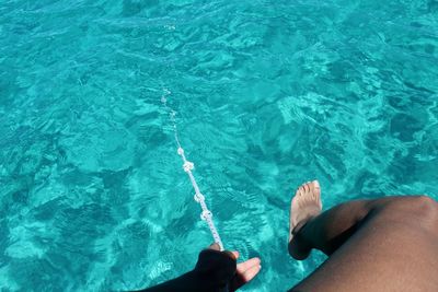 Low section of person holding string in sea