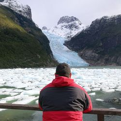 Rear view of man looking at snowcapped mountain