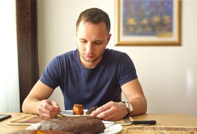 Man sitting with food in plate on table at home