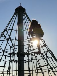 Low angle view of child on playground against clear sky
