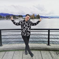 Portrait of smiling young woman standing on railing