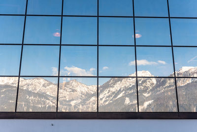 Reflection of sky and mountains on glass window wall.