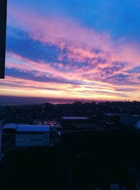 High angle view of silhouette buildings against sky at sunset