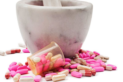 Multi colored pills with mortar and pestle over white background