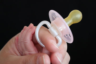 Close-up of hand holding toy against black background