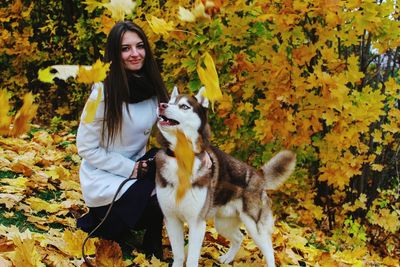 Portrait of young woman with dog in park during autumn