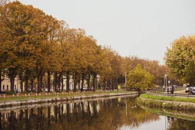 Trees by lake against sky during autumn