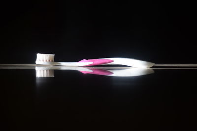 Close-up of pink flower on table against black background