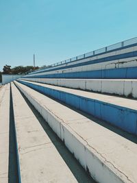 Empty footpath by building against clear blue sky