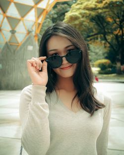 Portrait of beautiful young woman wearing sunglasses standing outdoors