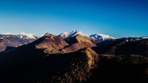 Scenic view of snowcapped mountains against clear blue sky