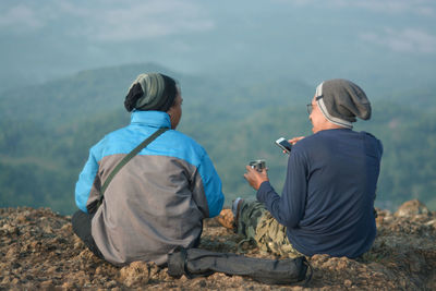 Rear view of men sitting on mountain