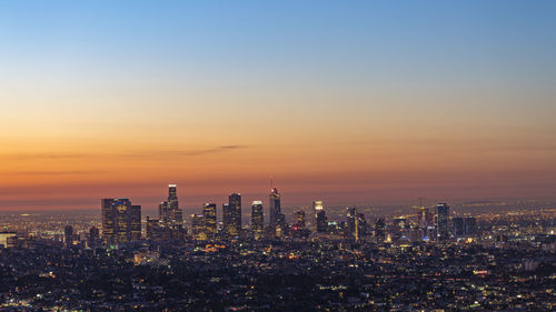 Illuminated cityscape against sky during sunset