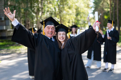 Rear view of woman wearing graduation gown standing outdoors