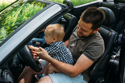 Rear view of woman holding steering wheel in car