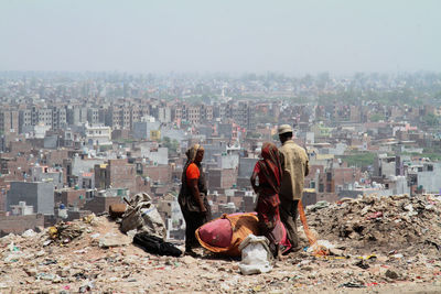 People working by buildings in city against sky