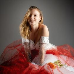 Portrait of young woman standing against gray background