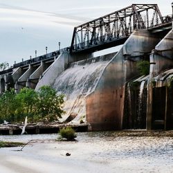 Built structure by dam against sky