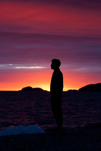 Silhouette man standing on beach against sky at sunset