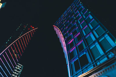 Low angle view of illuminated buildings against sky at night