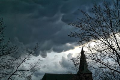 Low angle view of bare tree against cloudy sky