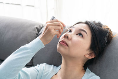 Young woman using mobile phone while lying on bed at home