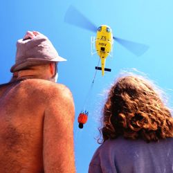 Low angle view of person holding hands against clear blue sky