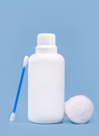 Close-up of white bottle on table against blue background