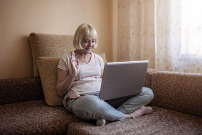 Full length of boy using laptop on sofa at home