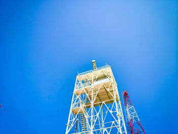 Low angle view of communications tower against clear blue sky