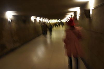 Blurred motion of people walking in illuminated tunnel