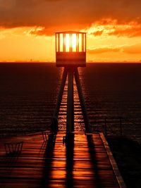 Pier over sea against sky during sunset