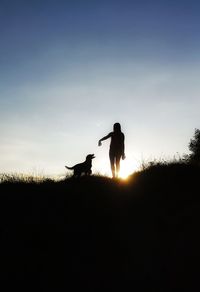 Silhouette man standing on field against sky during sunset