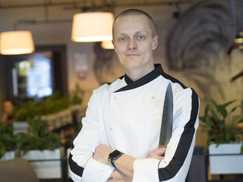 Portrait of confident chef with arms crossed standing at restaurant