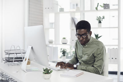 Young man using smart phone while sitting on table